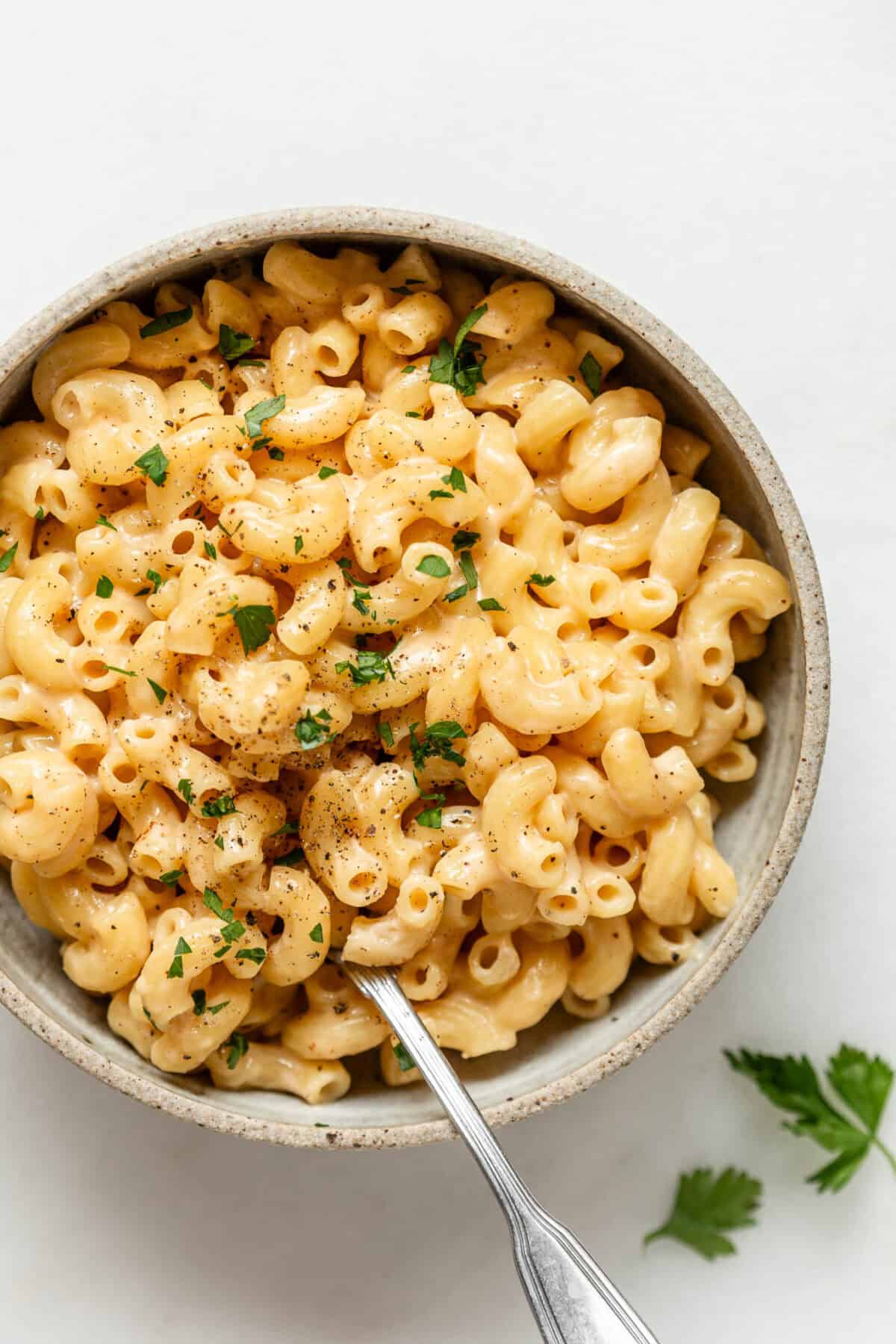 A bowl of cottage cheese mac and cheese with a spoon in it.