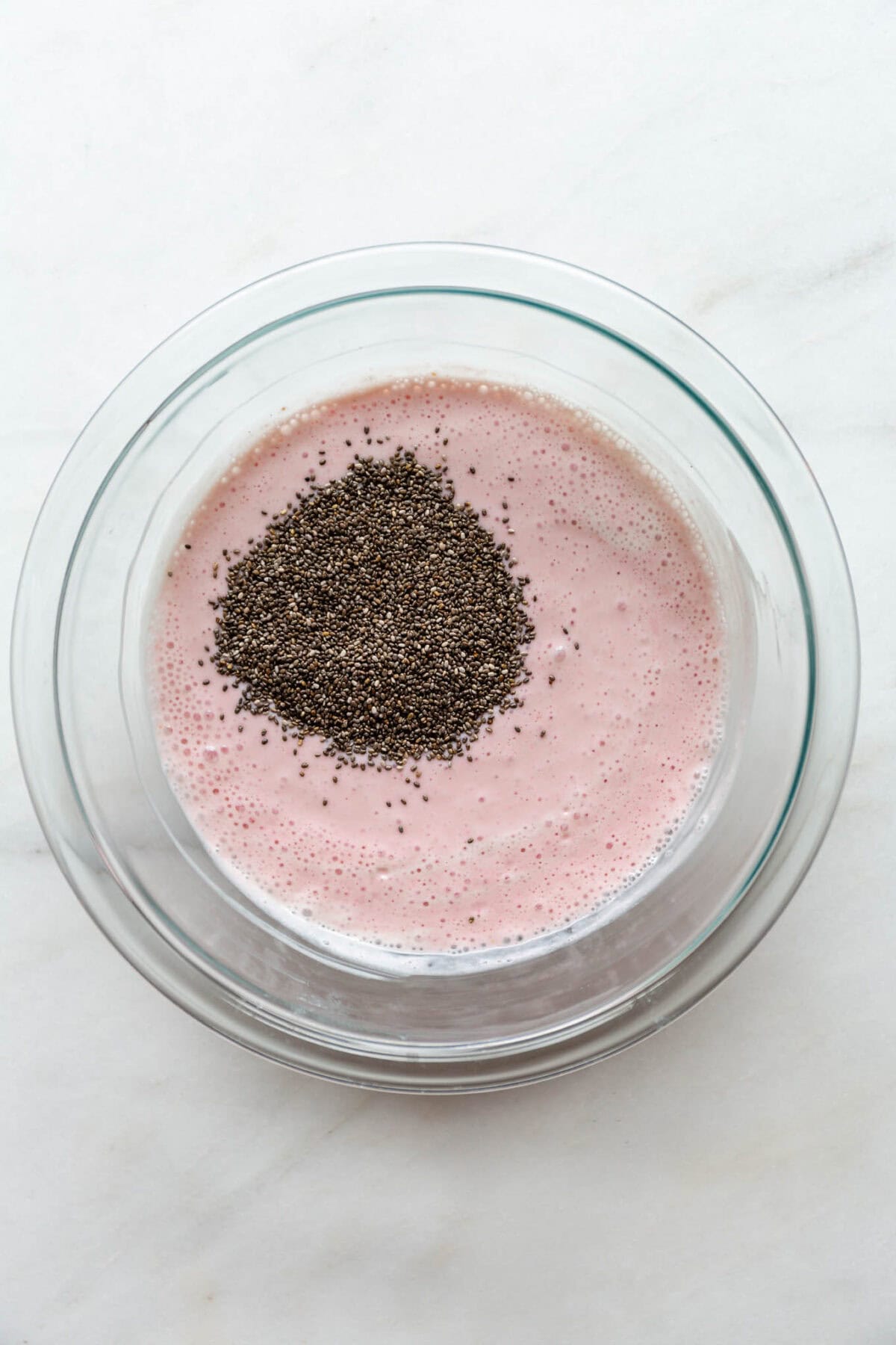 Blended raspberry cottage cheese in a clear bowl with chia seeds.