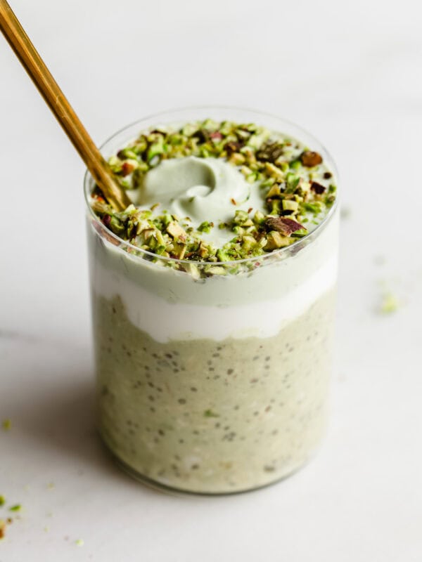 a cup of pistachio overnight oats with yogurt and crushed pistachios on top.