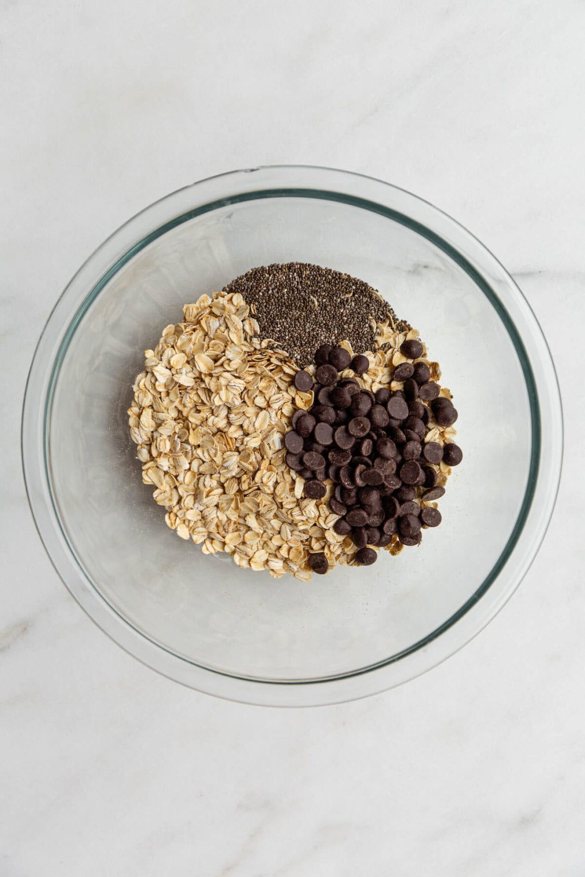 oats, chia seeds and chocolate chips in a clear mixing bowl.