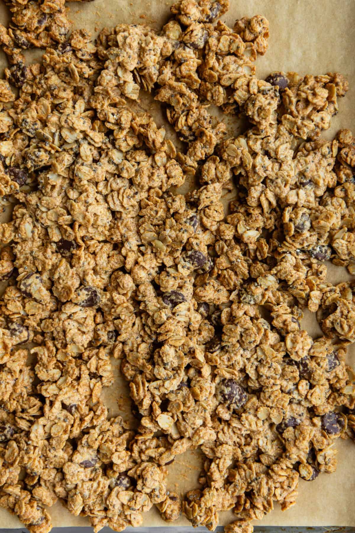 chocolate chip cookie dough granola on a baking pan with parchment paper.