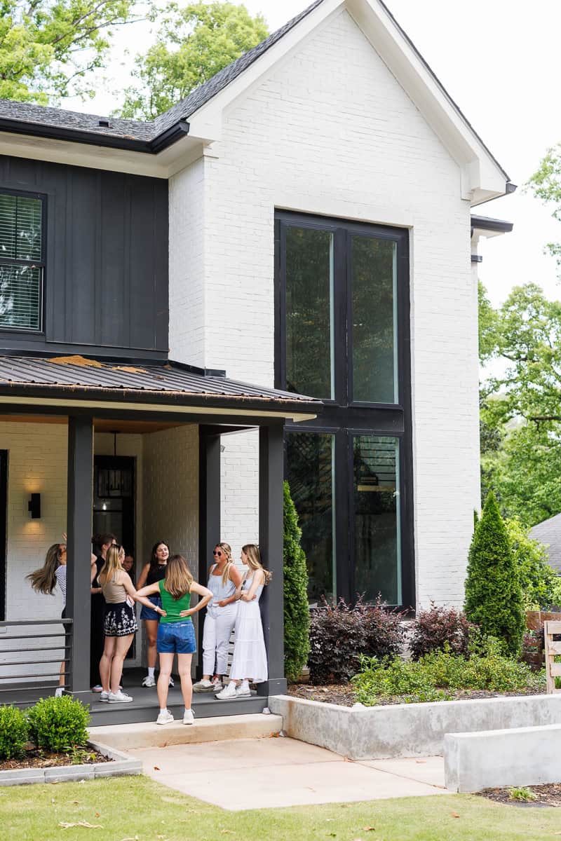 girls standing on the front porch of a house.