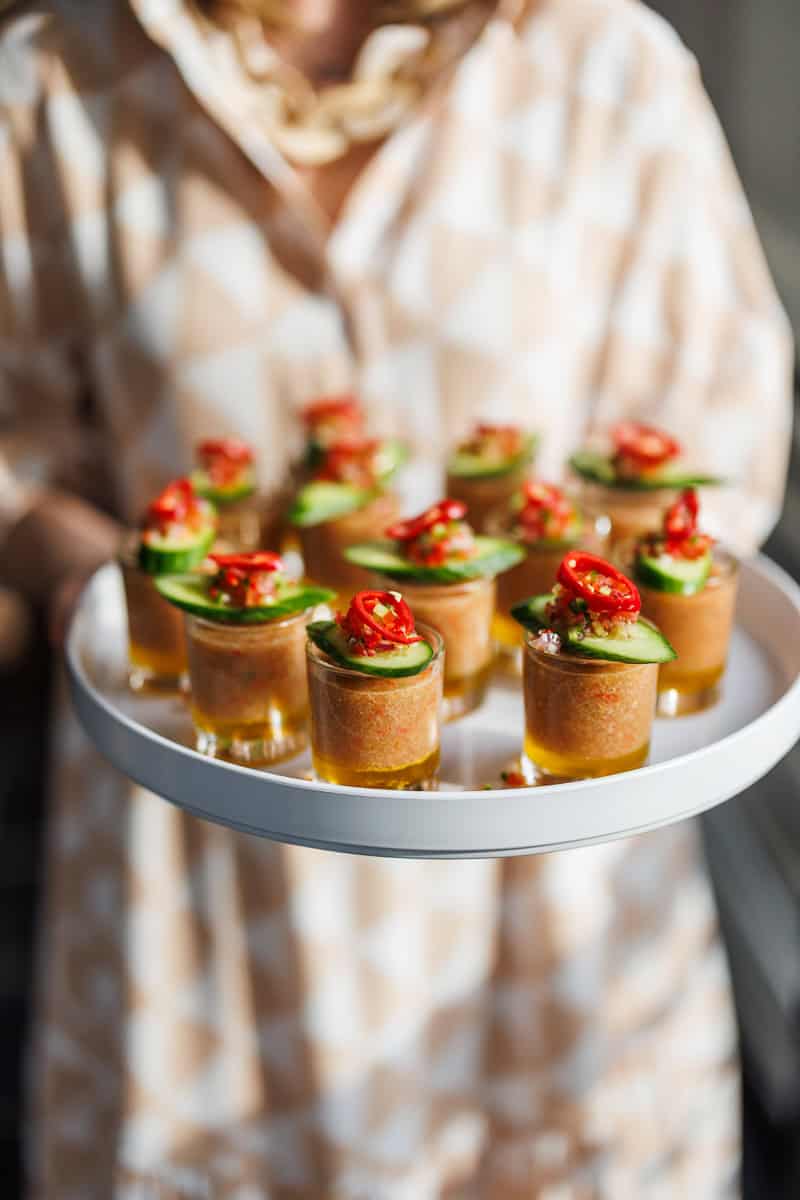 a person holding a tray of gaspacho