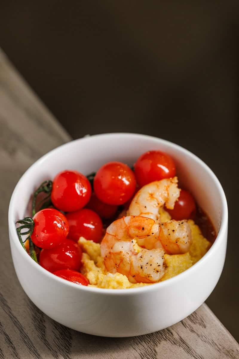 Shrimp, grits and cherry tomatoes in a bowl.