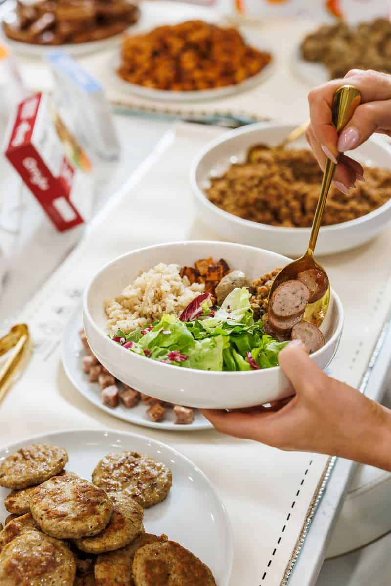a hand filling up a salad bowl.