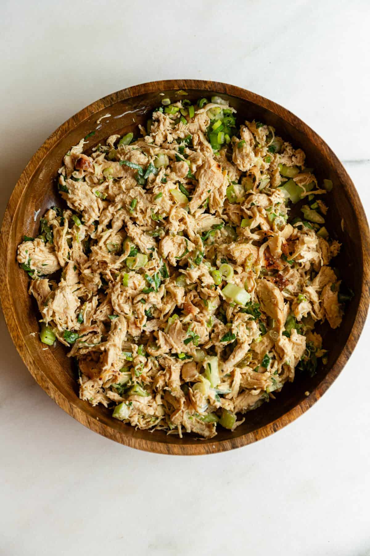 Overhead close-up of jalapeno popper chicken salad mixed together in a wooden bowl.