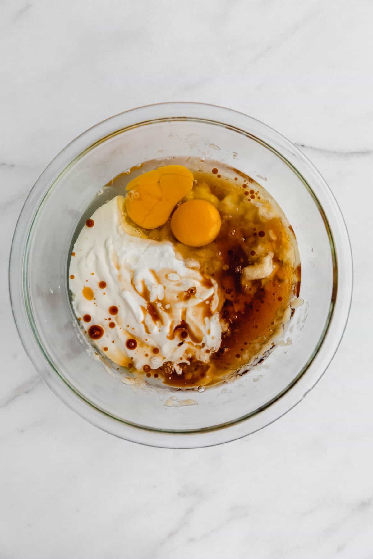 eggs, cottage cheese, maple syrup, and banana in a mixing bowl.