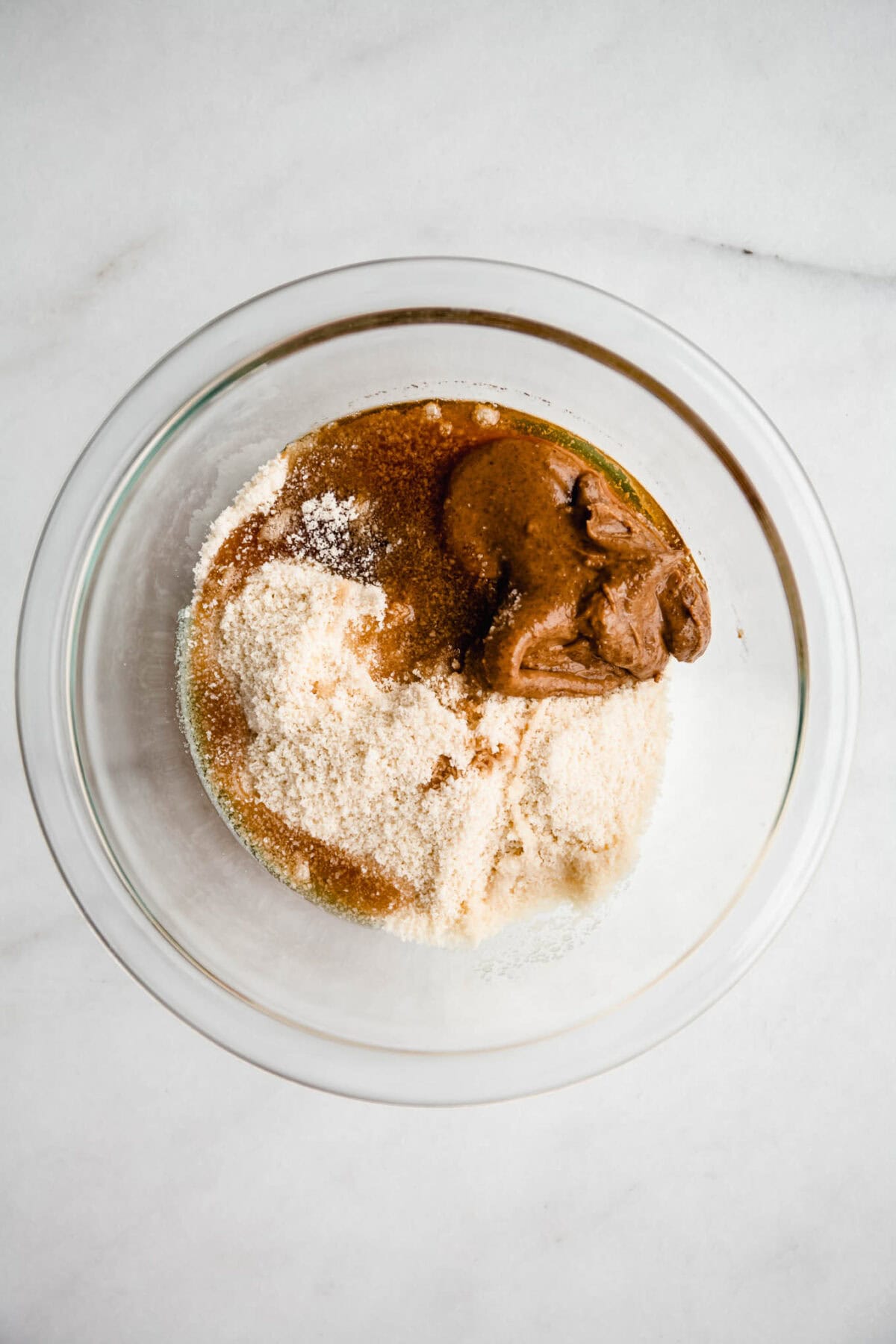 Almond flour, maple syrup and almond butter in a mixing bowl.