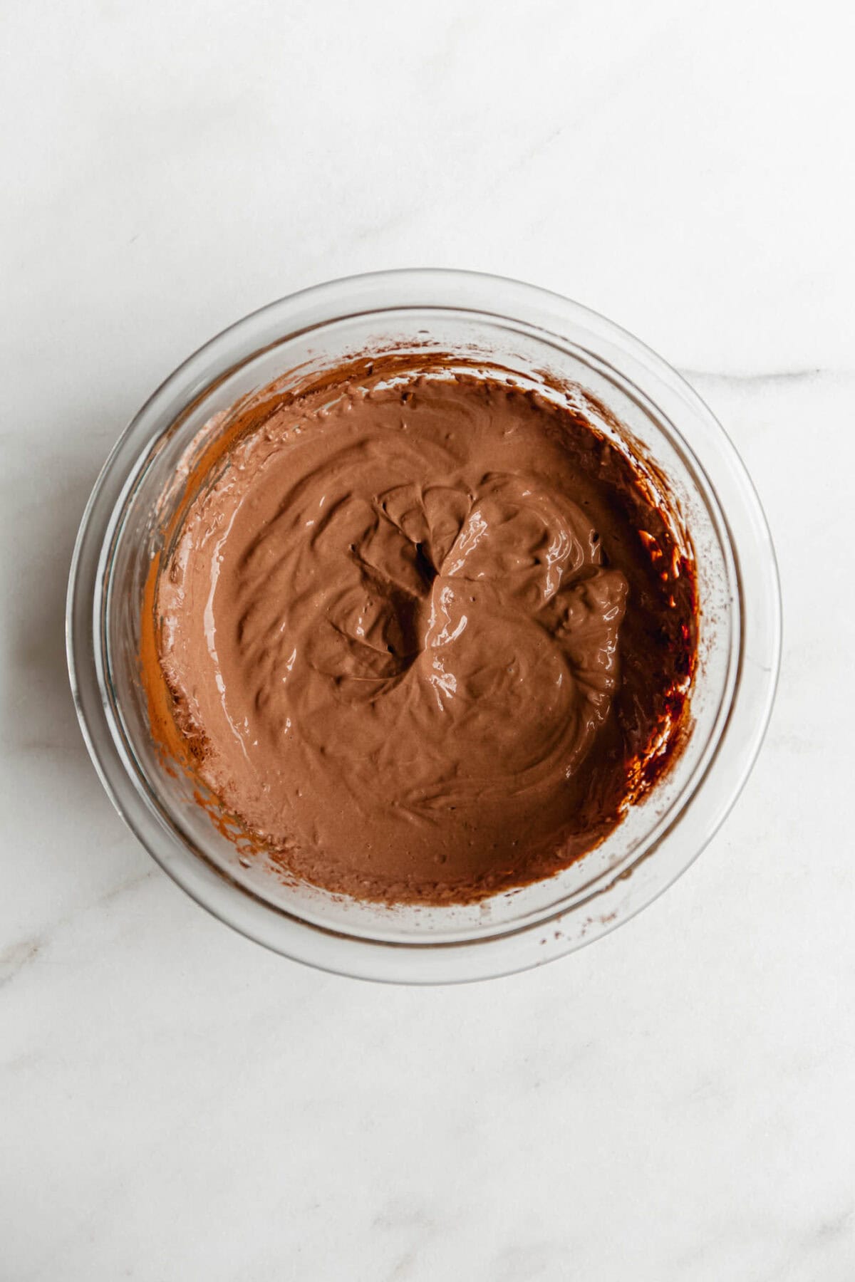 Greek yogurt chocolate mousse in a glass bowl, viewed from above on a white marble surface.