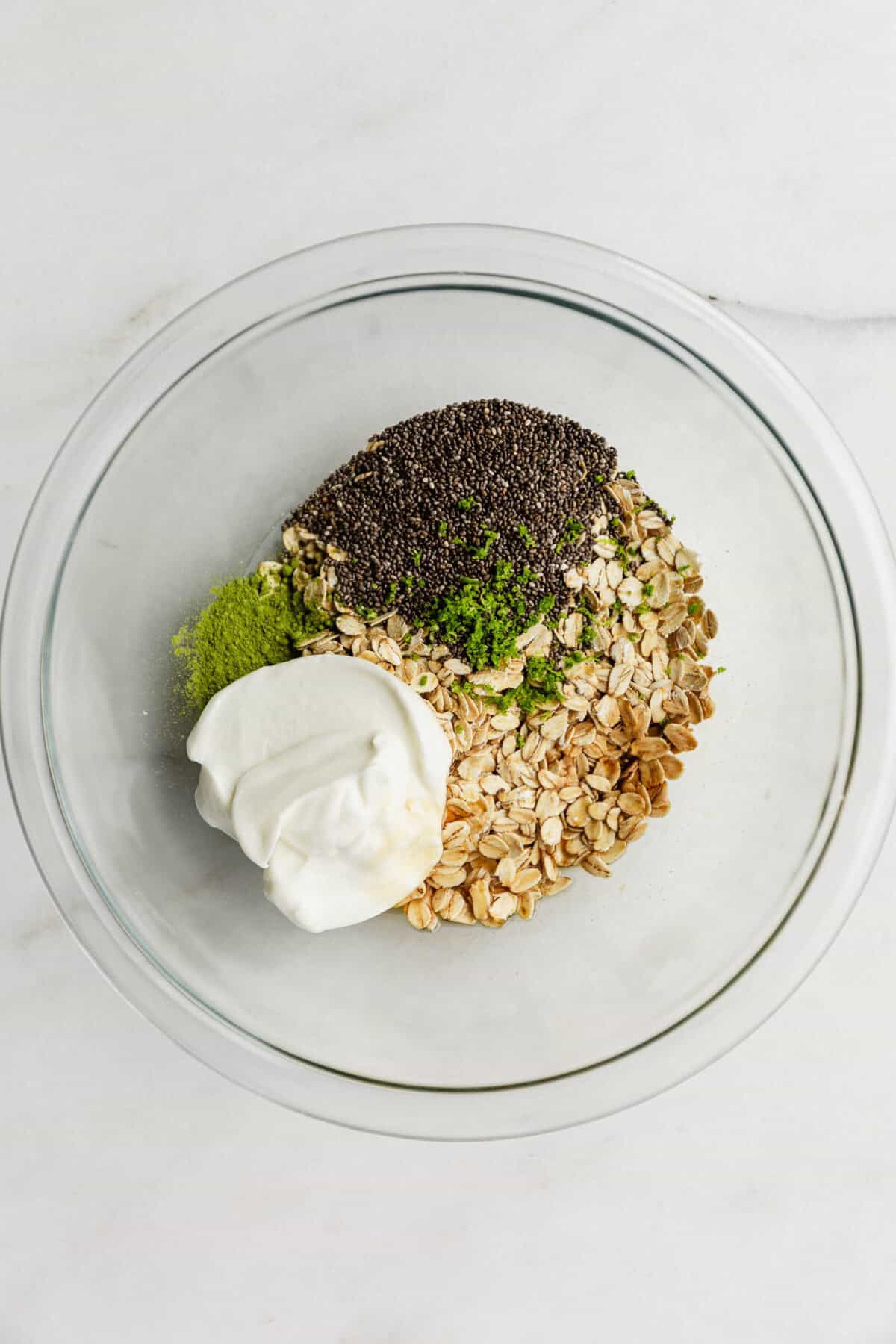 oats, chia seeds, yogurt, lime zest and matcha powder in a clear bowl.