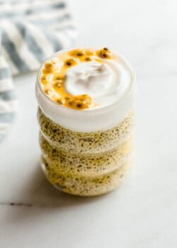 Glass jar of passionfruit chia pudding with layers of chia pudding topped with creamy yogurt and passionfruit pulp.