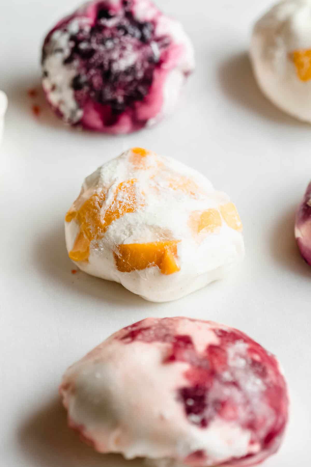 Mango, strawberry and blueberry rice paper mochi on a marble surface.
