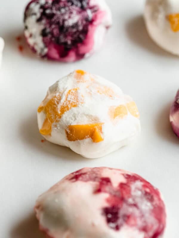 Mango, strawberry and blueberry rice paper mochi on a marble surface.