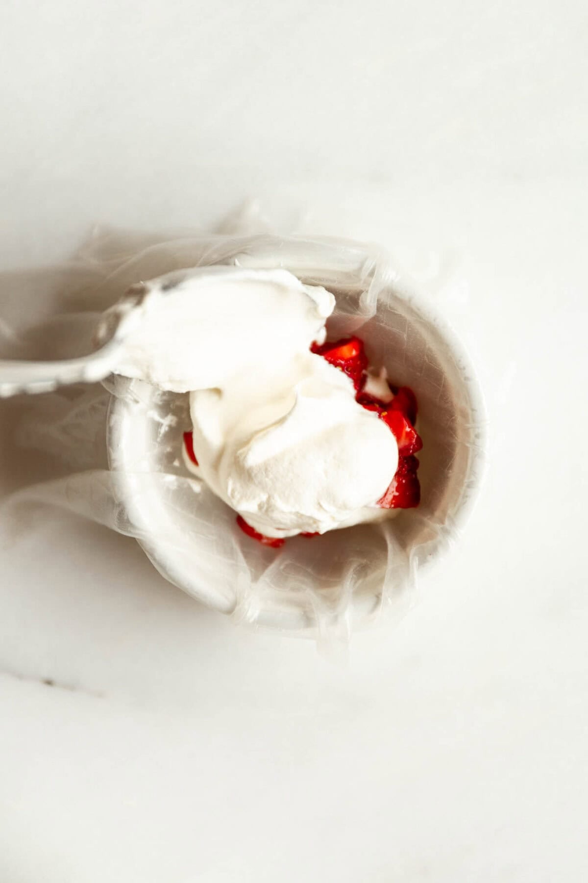 Rice paper dough being wrapped around strawberry filling to make mochi