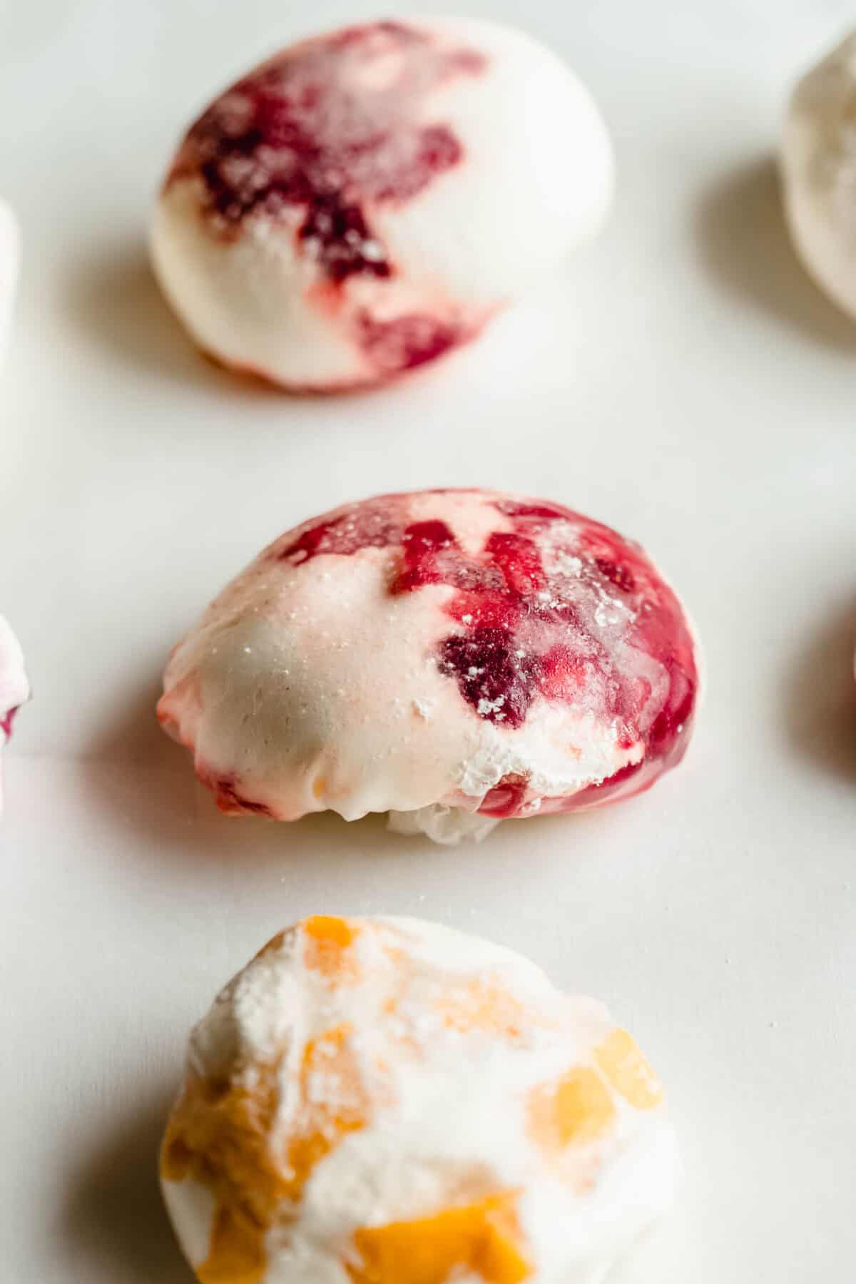 Three rice paper mochi balls filled with strawberry, blueberry and mango
