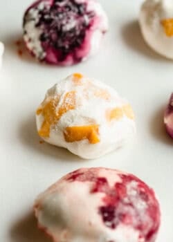 Rice paper mochi balls with blueberry and mango fillings on a white surface.