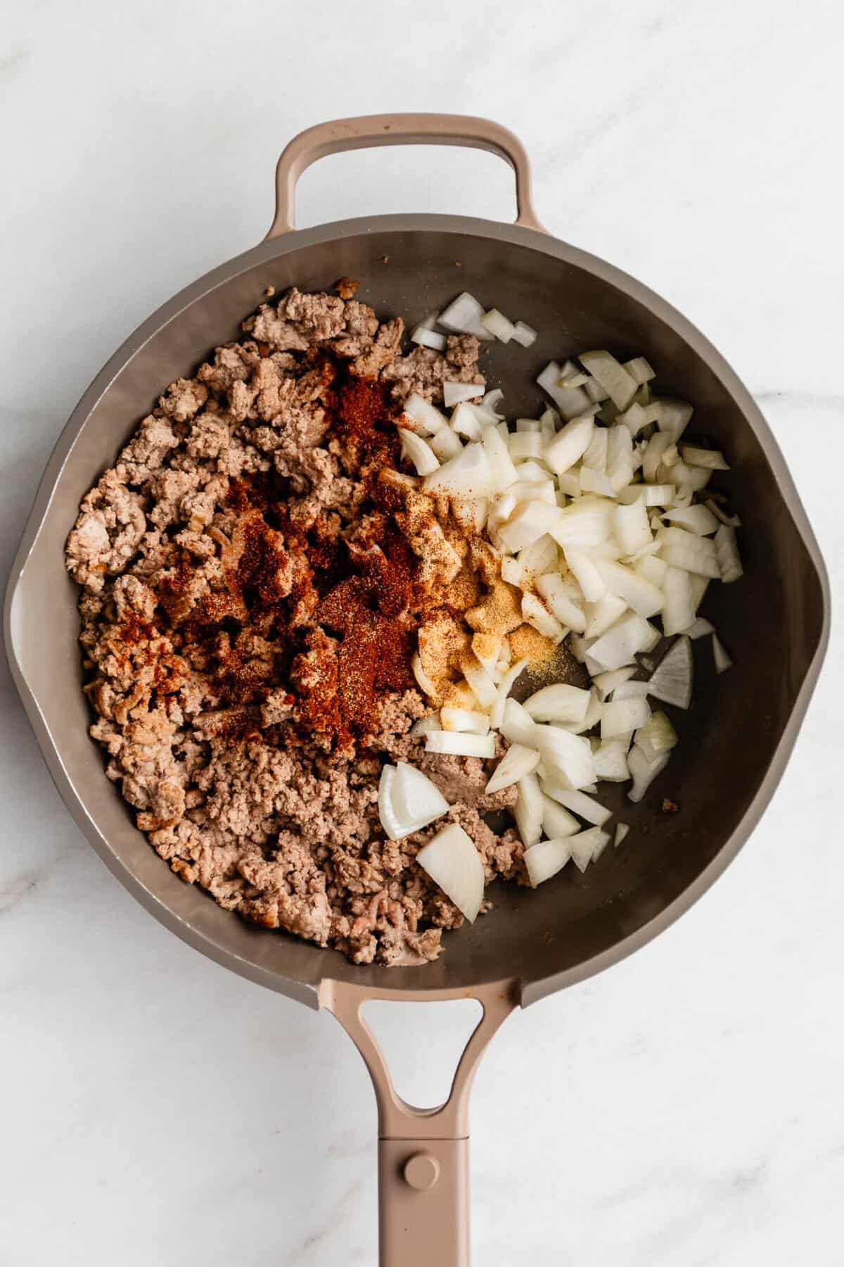 ground turkey, onion and seasoning in a taupe pan.