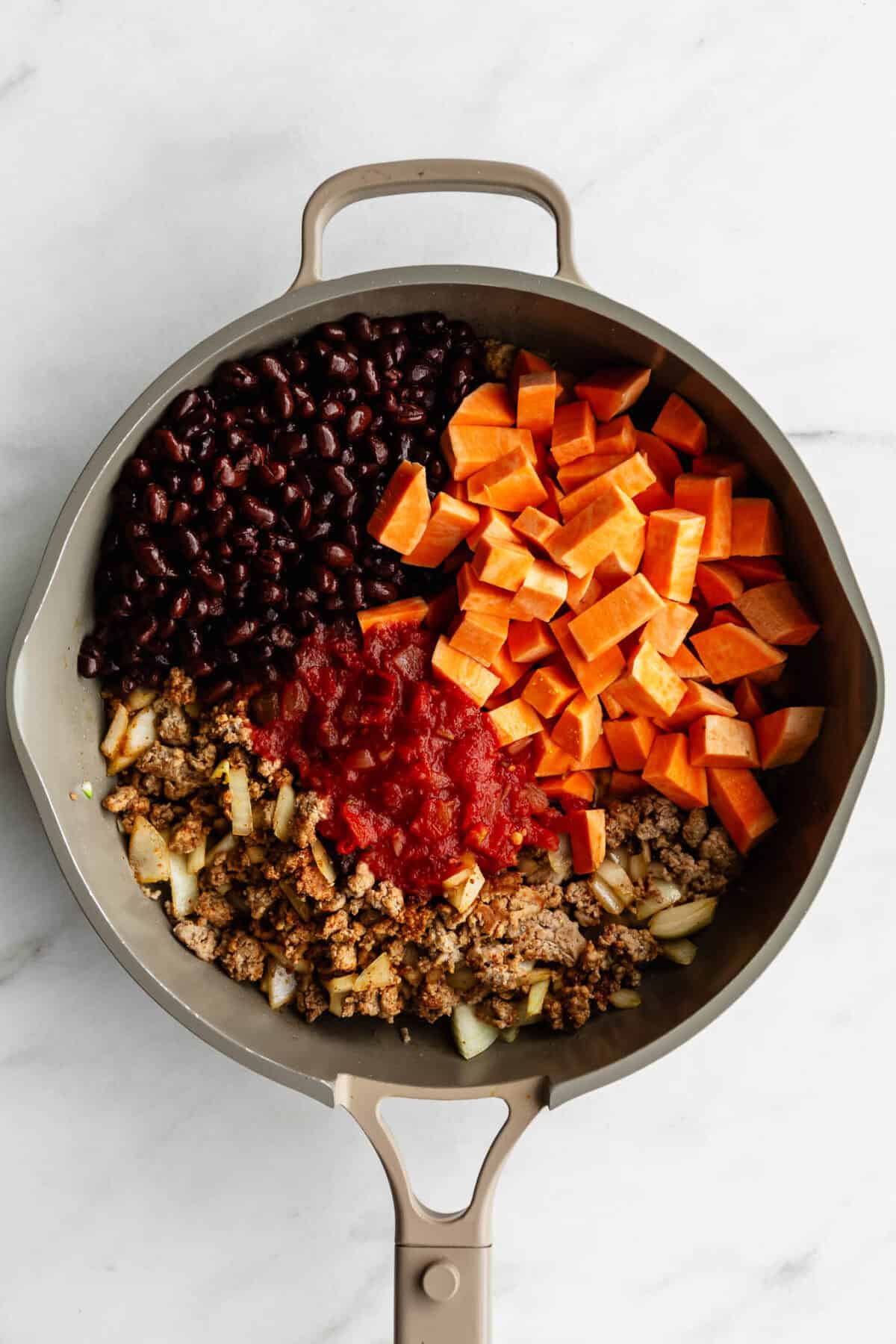 ground turkey, sweet potato, salsa and black beans in a taupe pan.