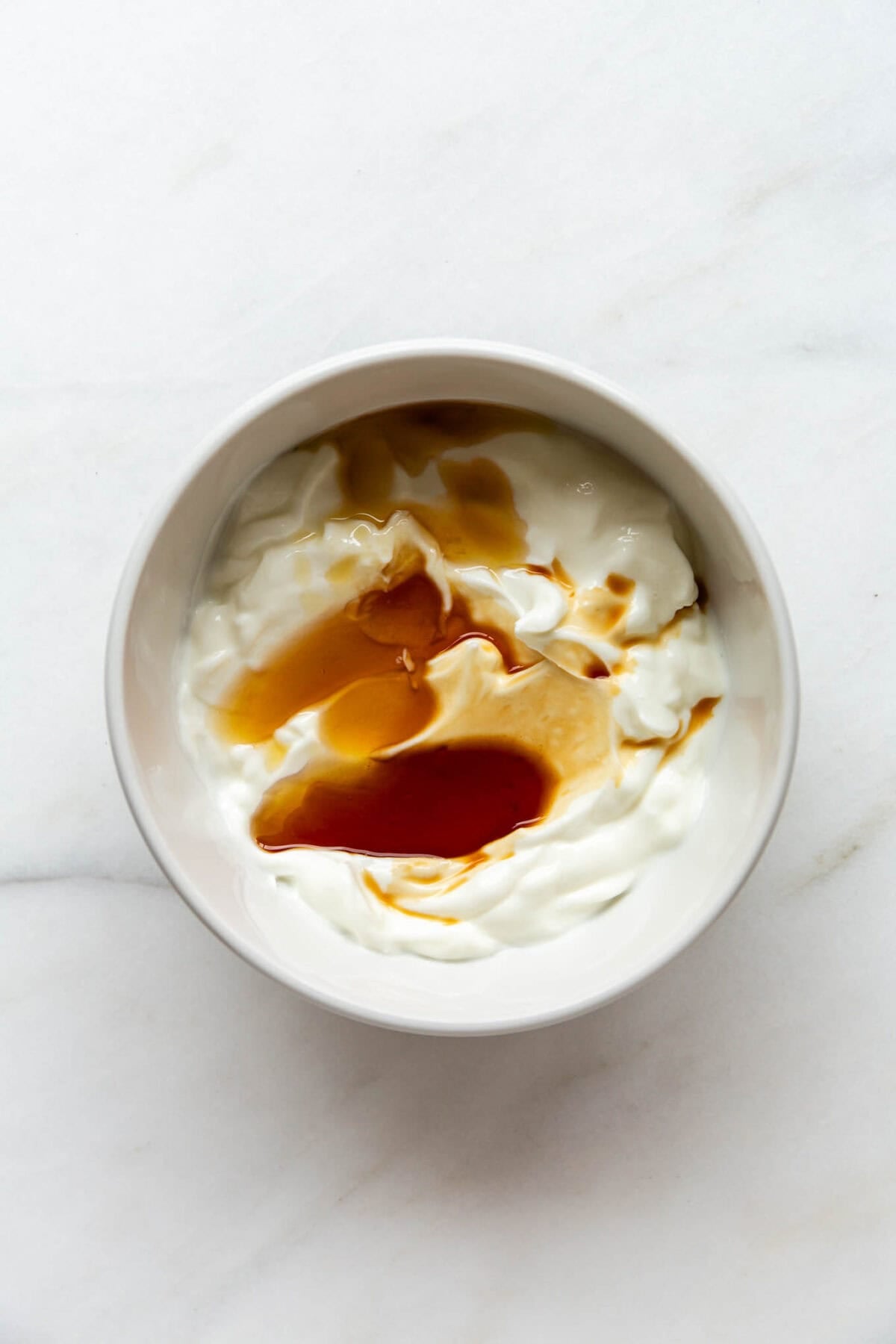 A bowl of Greek yogurt with maple syrup and vanilla.