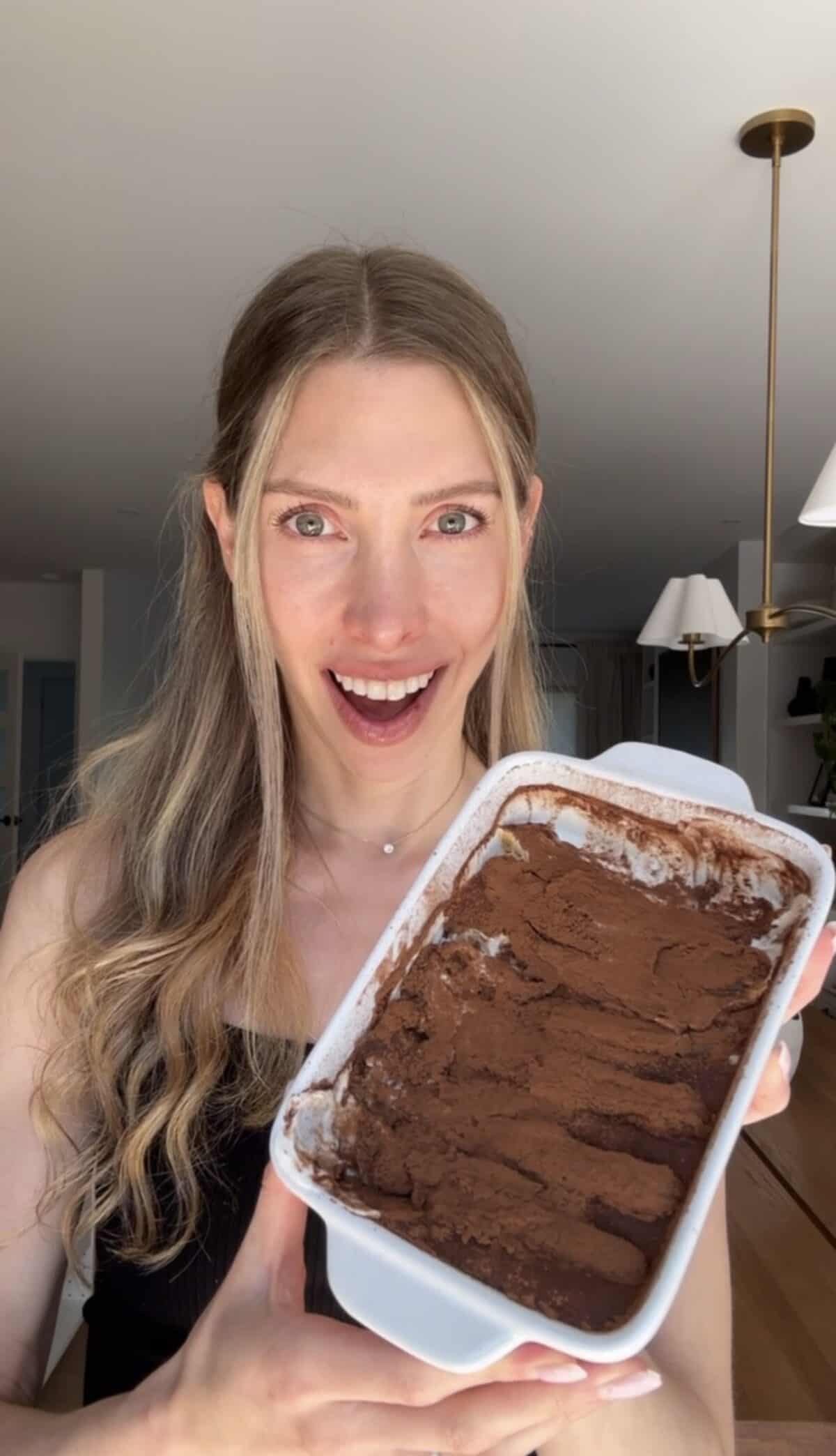 A girl holding a baking dish of Greek yogurt tiramisu.