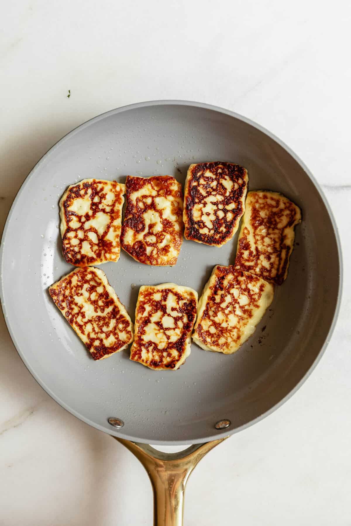 halloumi cheese sliced in a frying pan.