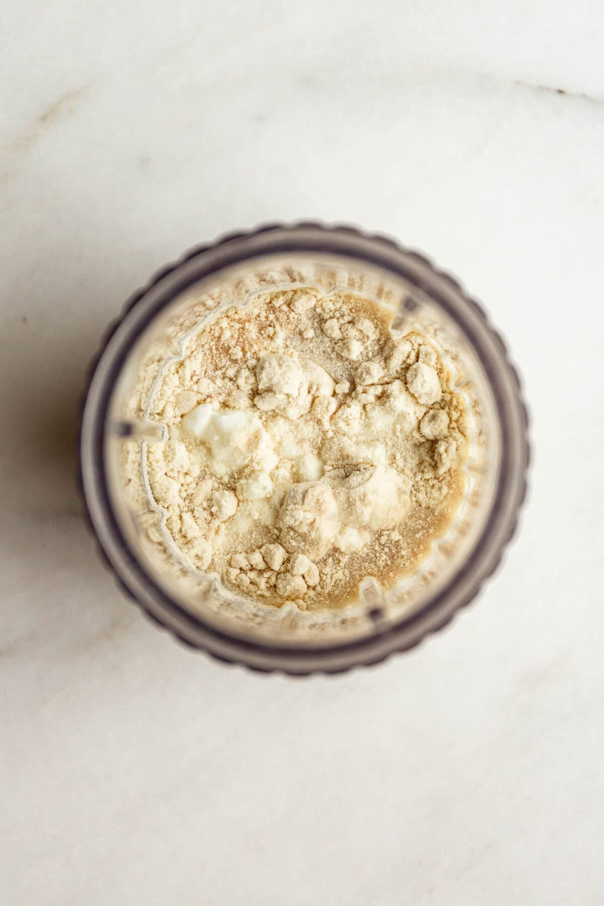 Top down view of a blender container with cottage cheese, milk and protein powder.