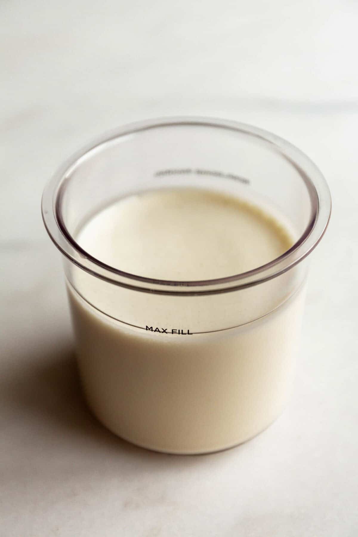 Cookies and cream Ninja Creami base mixture in a Ninja Creami container filled to the max fill line.