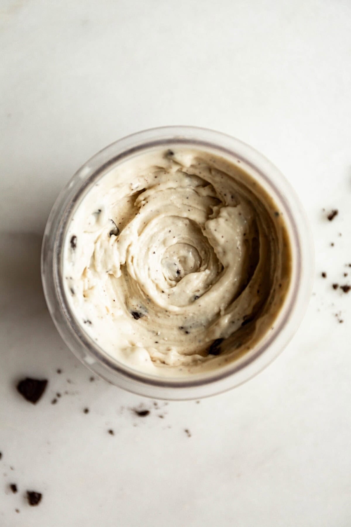 Top down view of cookies and cream Ninja Creami with Oreo cookie pieces mixed in, showing the creamy swirled ice cream texture.