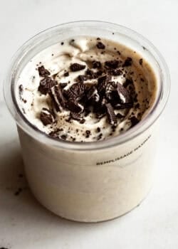 Cookies and cream Ninja Creami in a container topped with crushed Oreo cookies and chocolate cookie pieces.