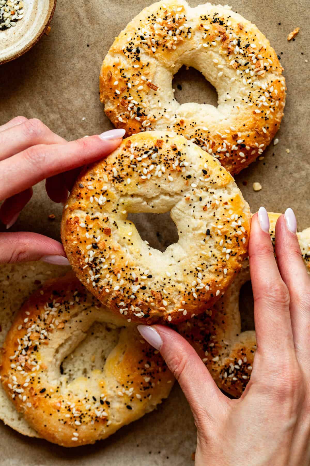 Two hands holding a Cottage Cheese Almond Flour Bagel.