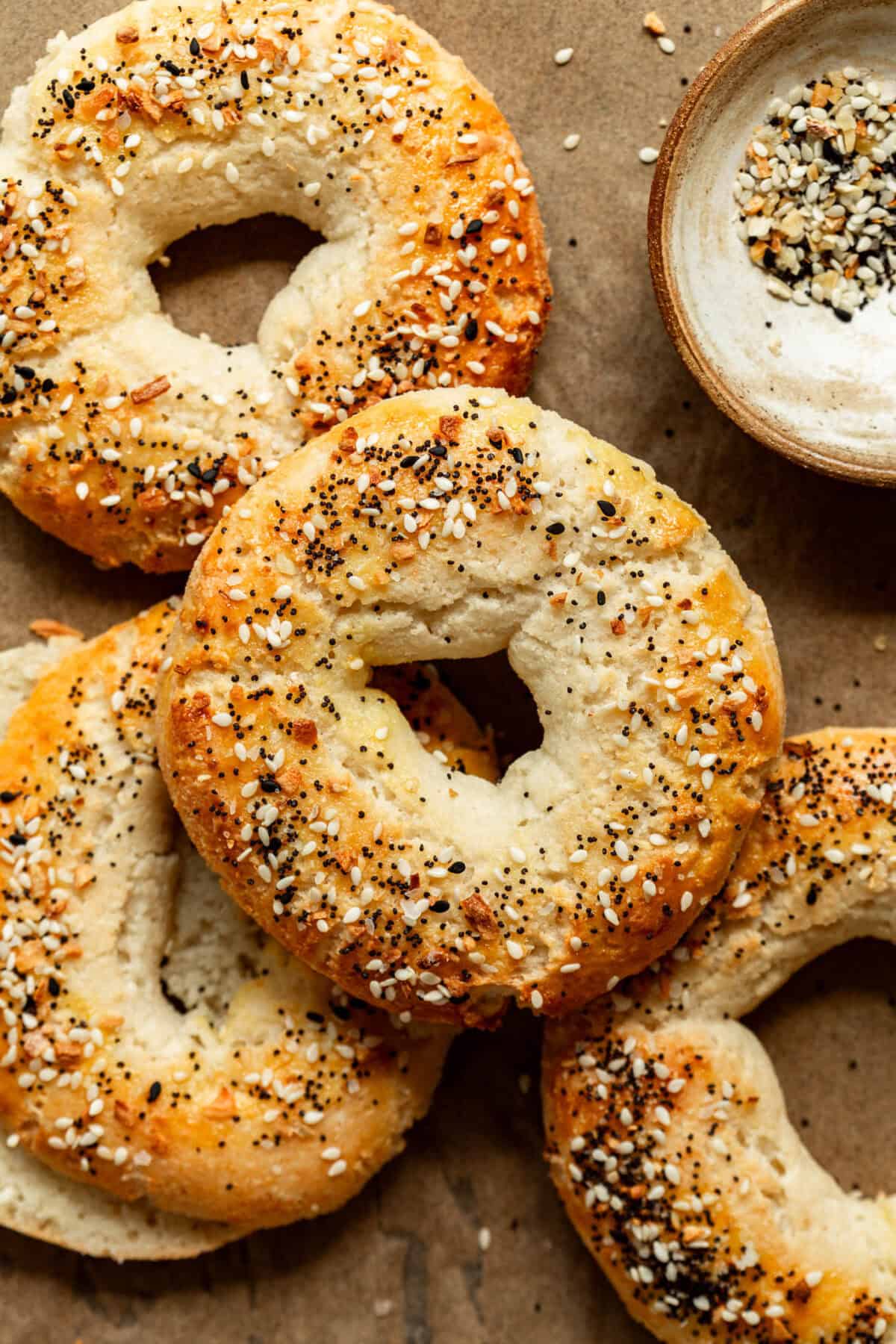 Cottage Cheese Almond Flour Bagels on parchment paper with a small bowl of everything bagel spice on the side.