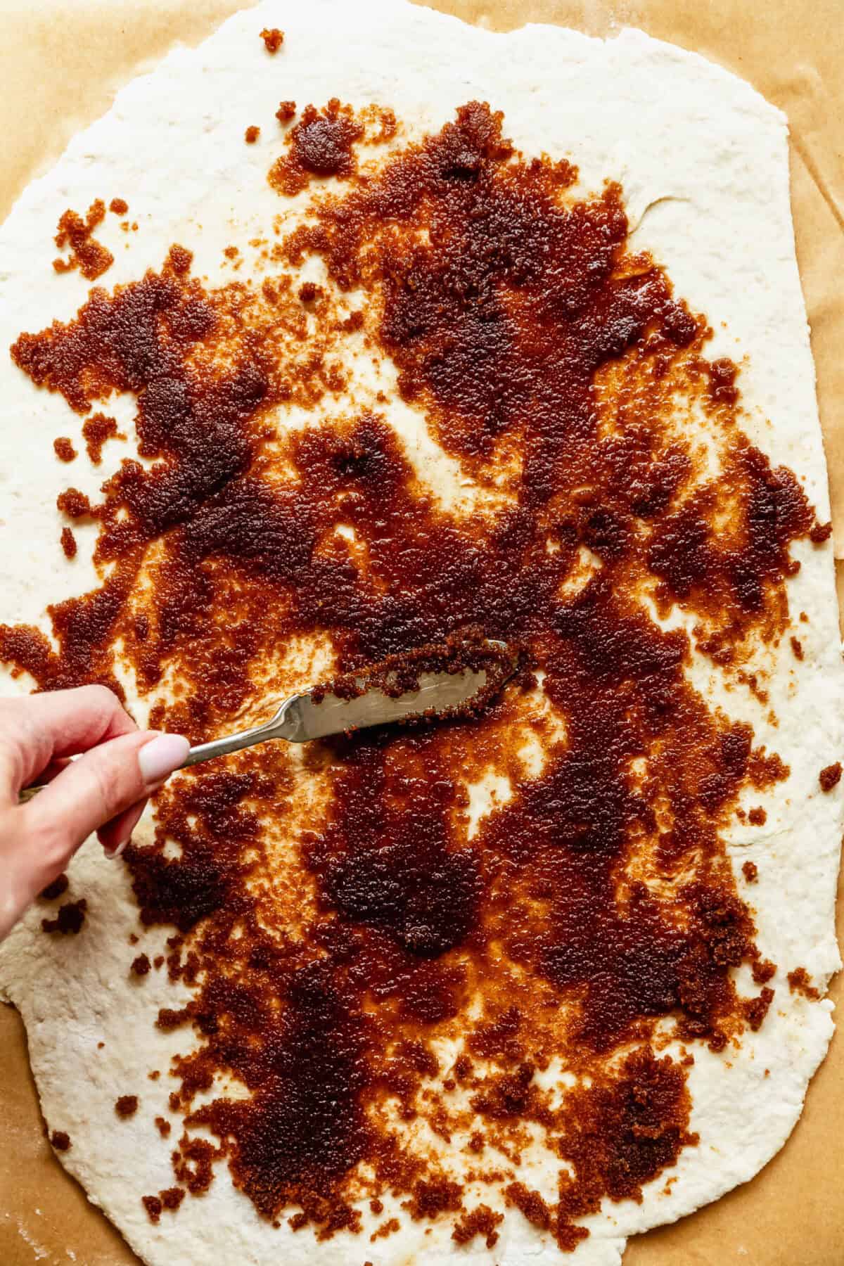 spreading cinnamon roll filling onto dough.