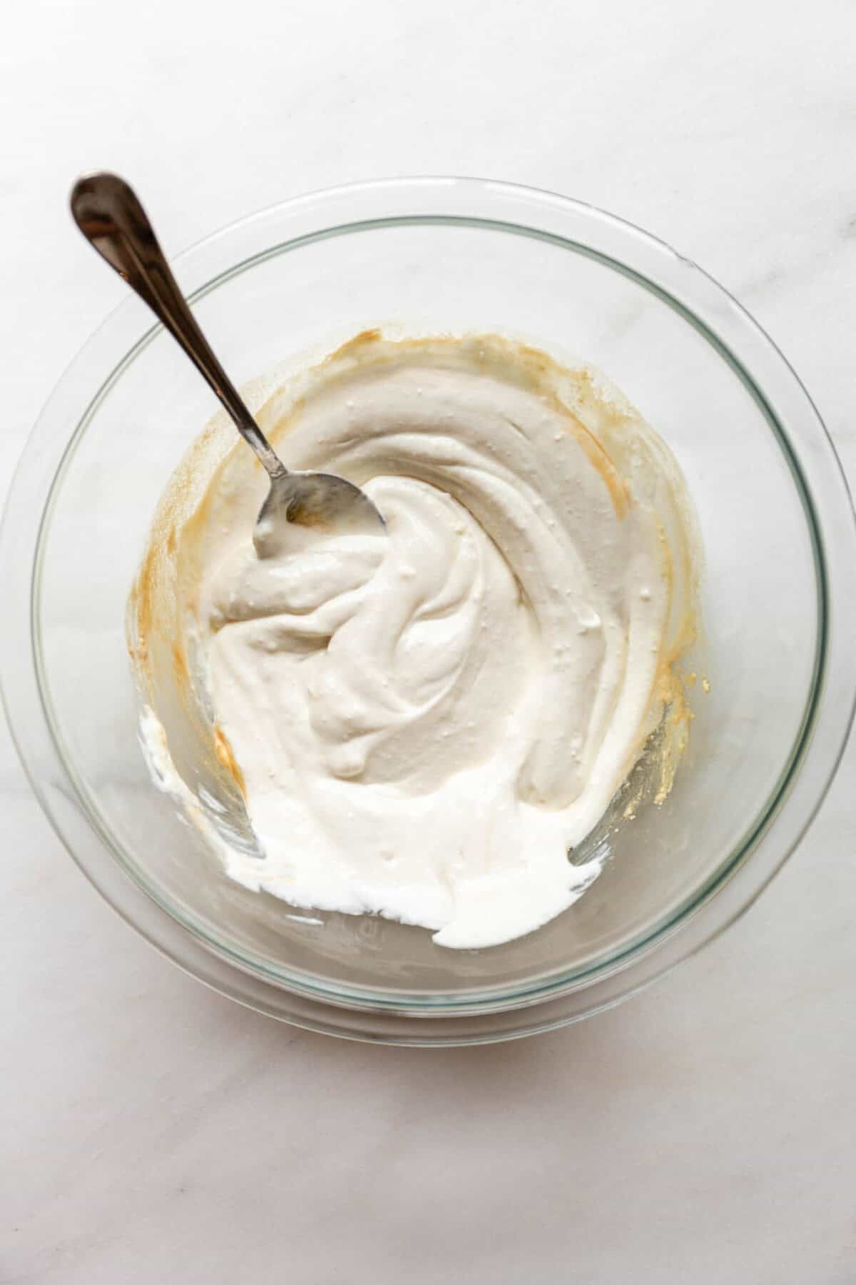 Mixing cottage cheese in a clear bowl with a spoon.