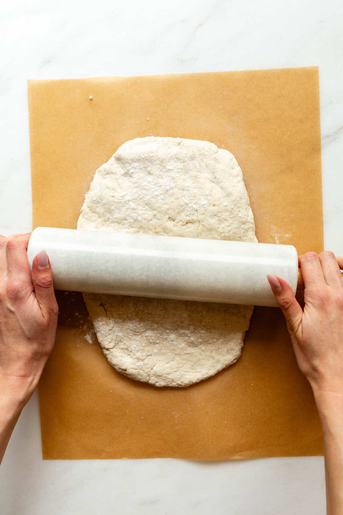Rolling out cottage cheese cinnamon roll dough with a rolling pin.
