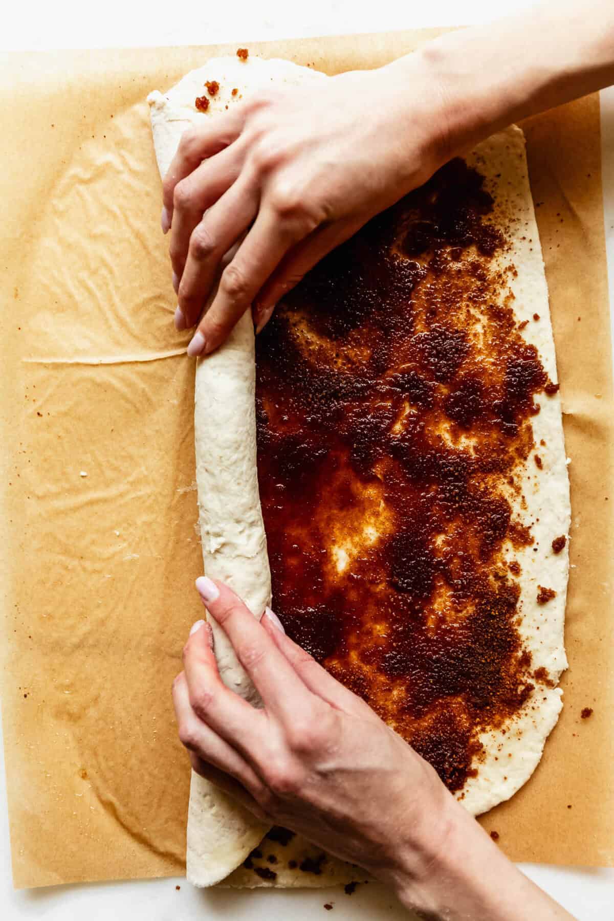 hands rolling up cottage cheese cinnamon roll dough.