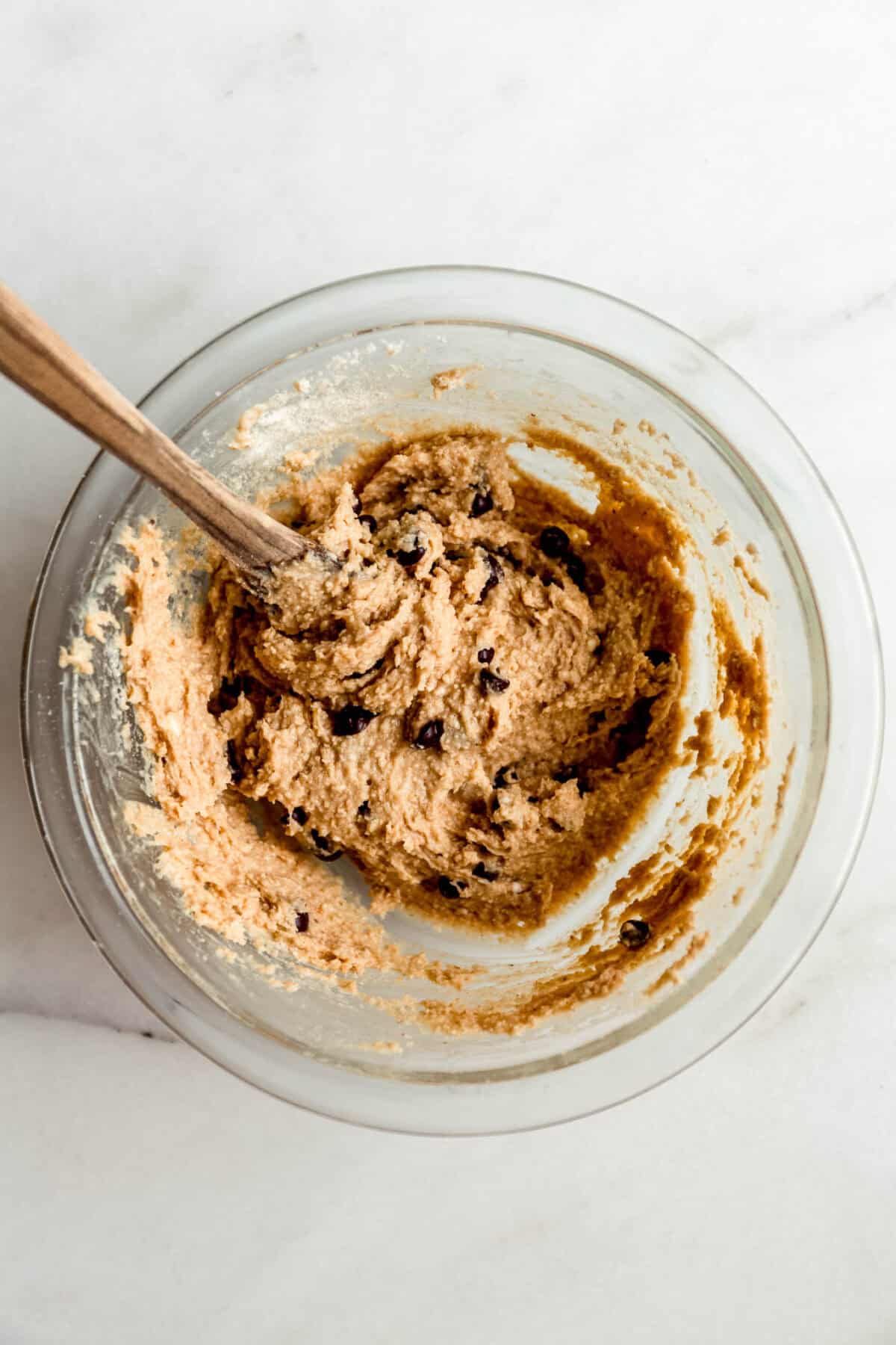 Cottage cheese cookie dough in a clear mixing bowl with a wood spoon.