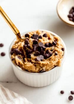 Cottage cheese cookie dough in a white ramekin with a gold spoon in it.