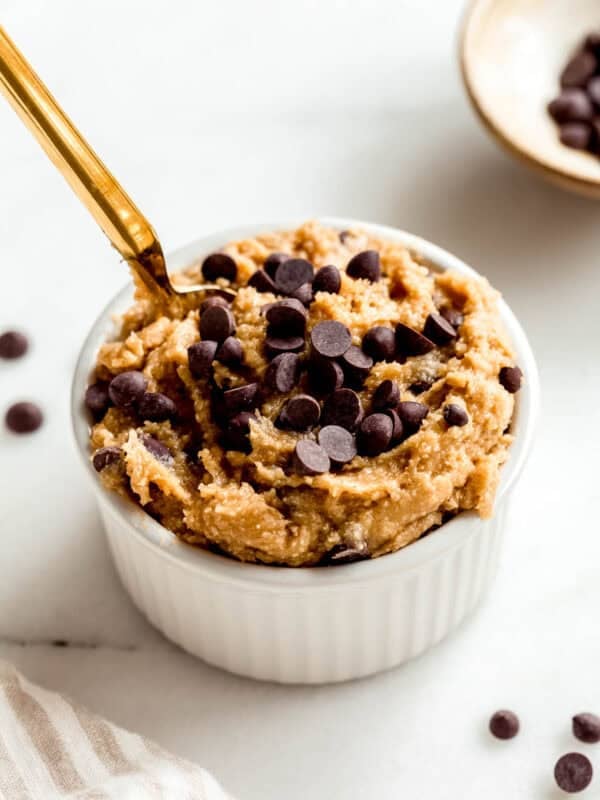 Cottage cheese cookie dough in a white ramekin with a gold spoon in it.
