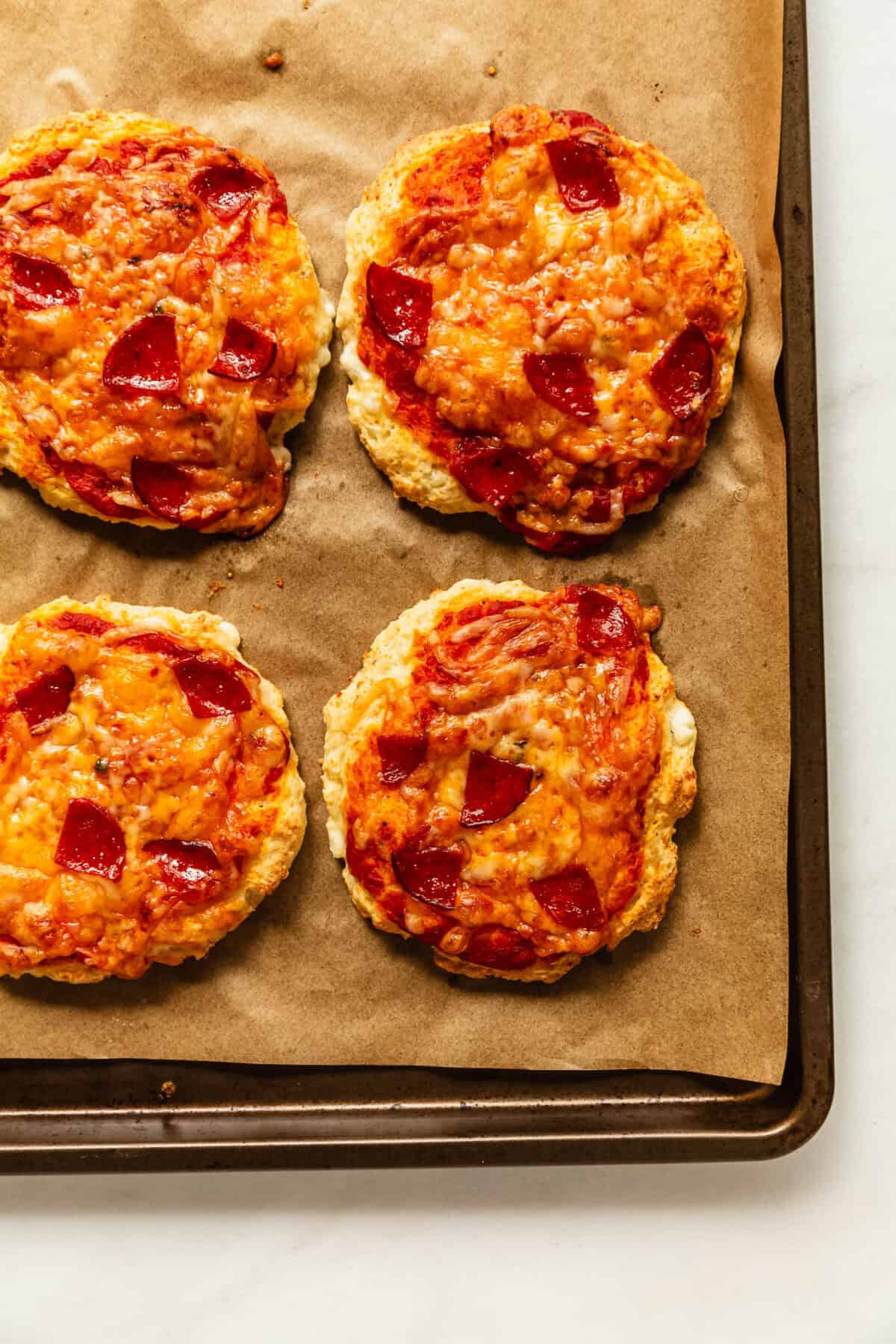 four cottage cheese pizza buns on a baking sheet.