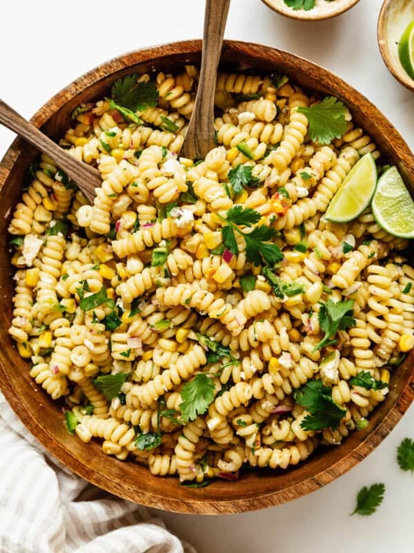 elote pasta salad in a wood bowl with wooden spoons.