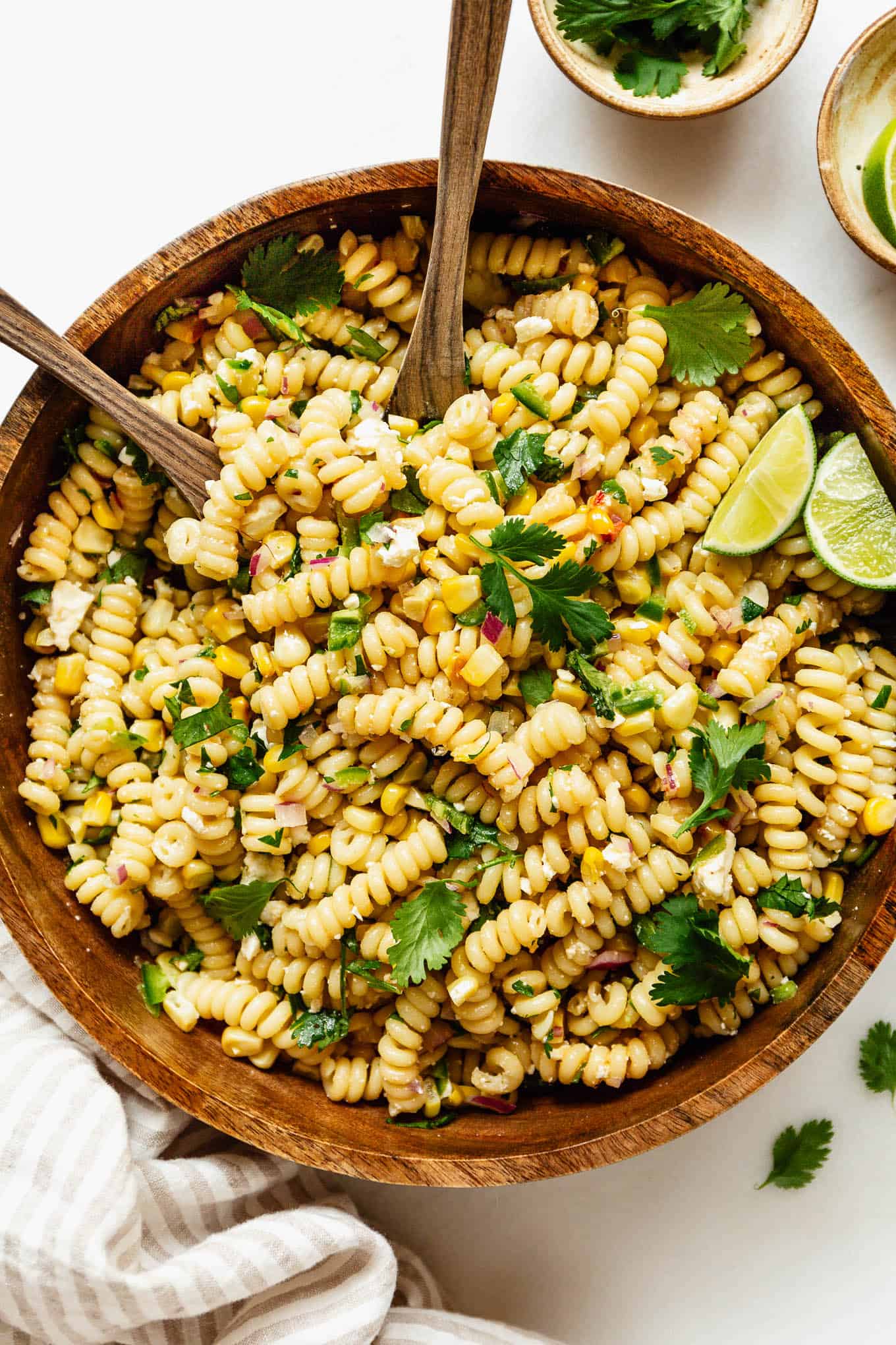 elote pasta salad in a wood bowl with wooden spoons.