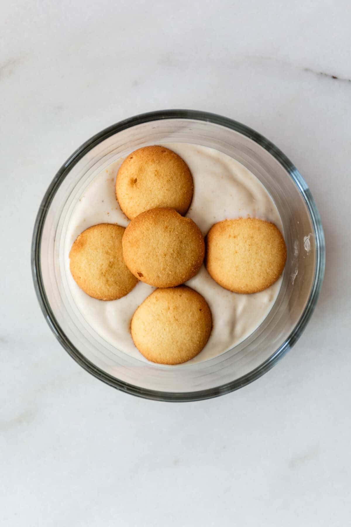High protein banana pudding topped with vanilla wafer cookies in a glass bowl.
