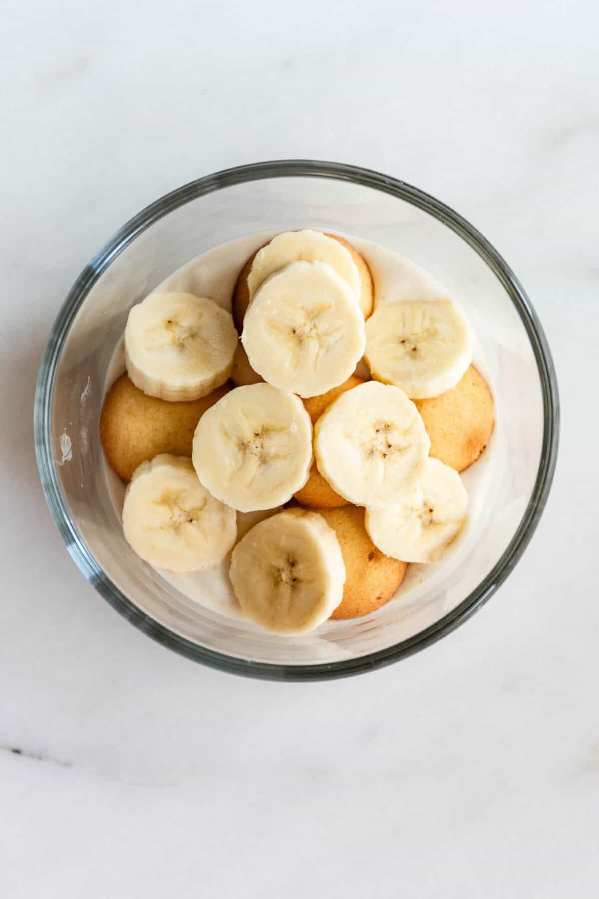 High protein banana pudding topped with fresh banana slices in a glass bowl.