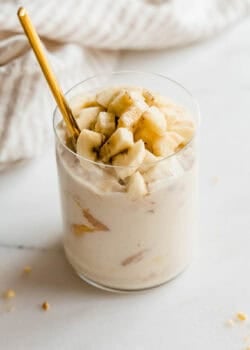 Glass jar of high protein banana pudding being scooped with a gold spoon.