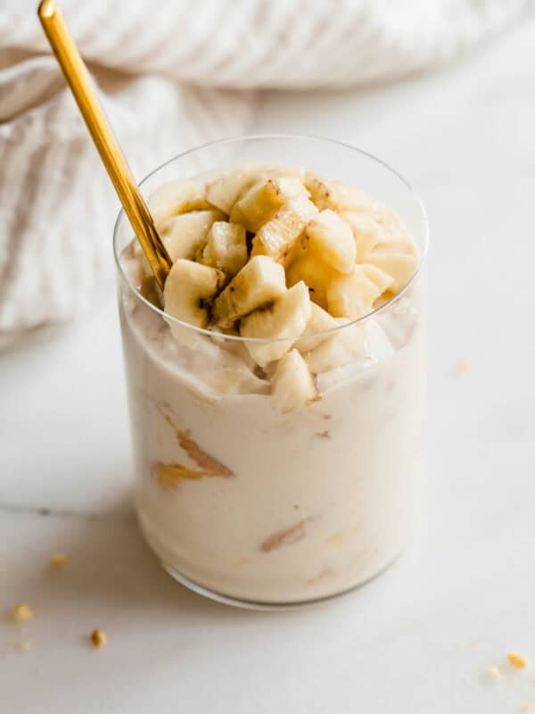 Glass jar of high protein banana pudding being scooped with a gold spoon.