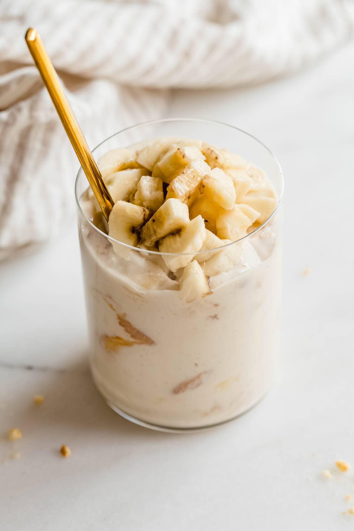 Glass jar of high protein banana pudding being scooped with a gold spoon.