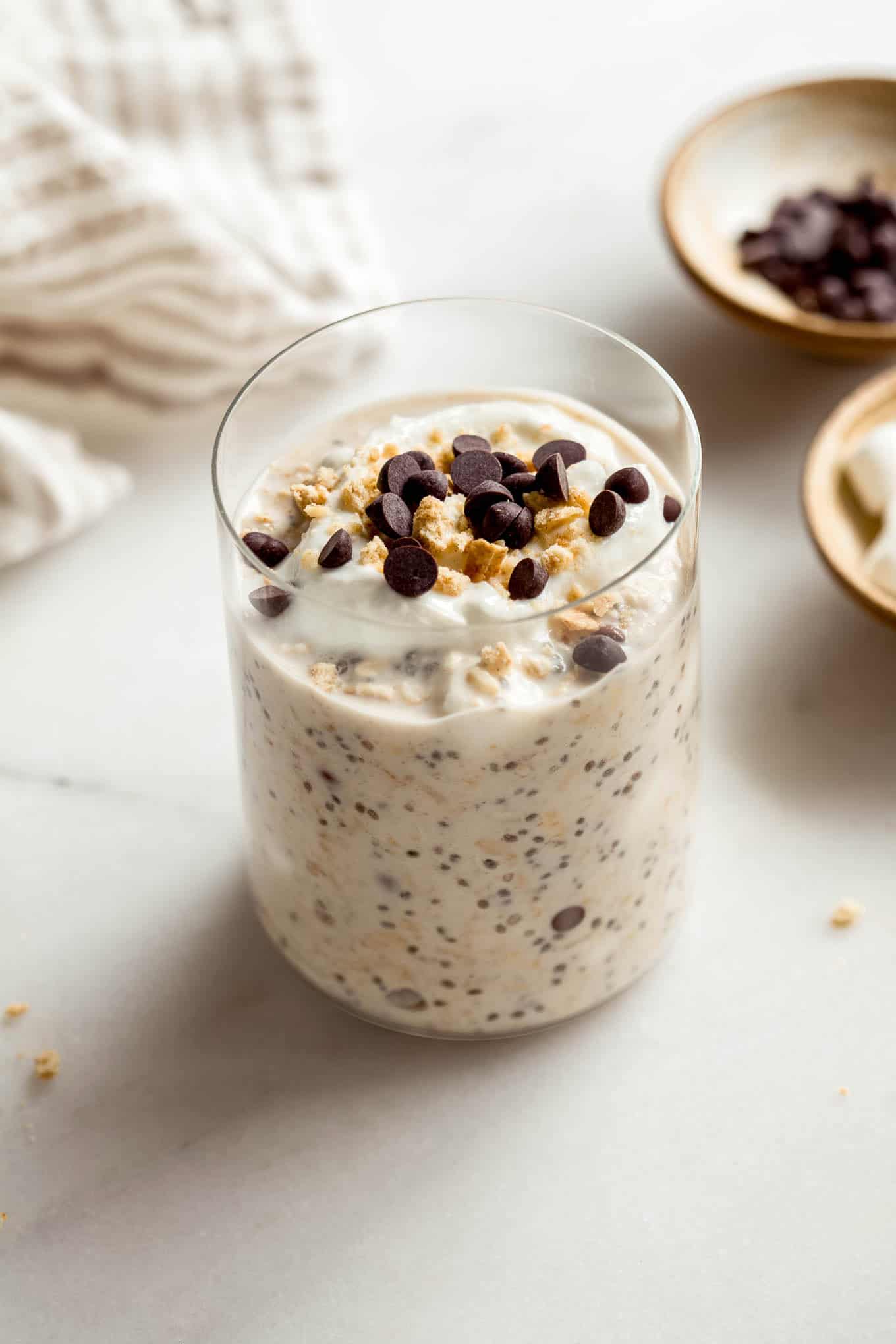A jar of smores overnight oats topped with graham cracker crumbs and chocolate chips.