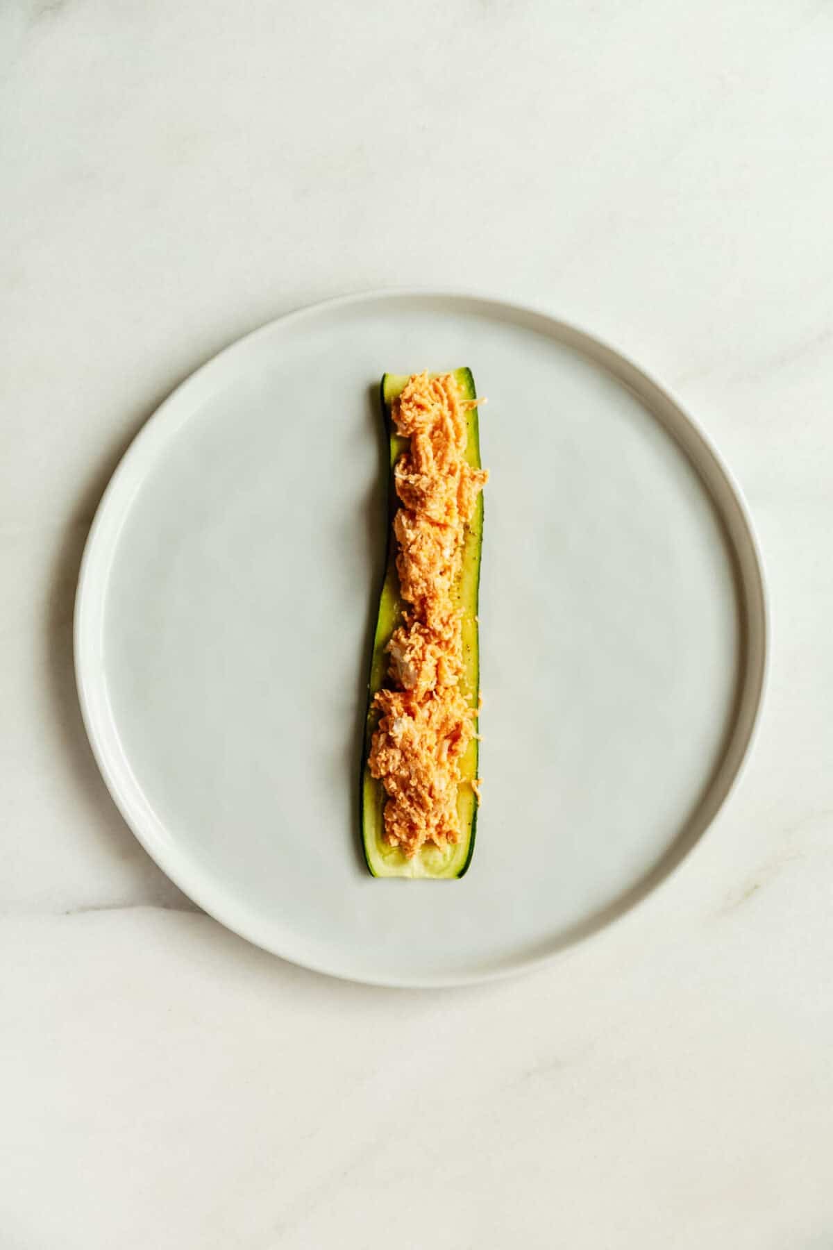 a sliced zucchini topped with buffalo chicken filling.
