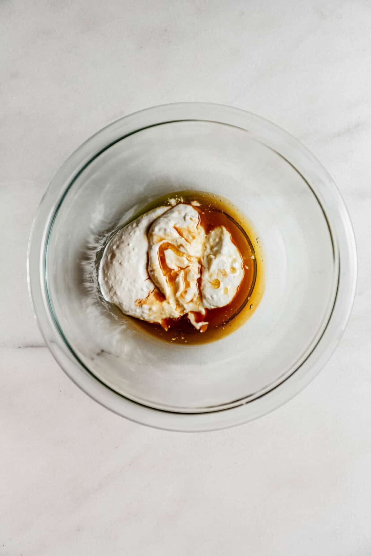 cottage cheese and maple syrup in a clear mixing bowl.