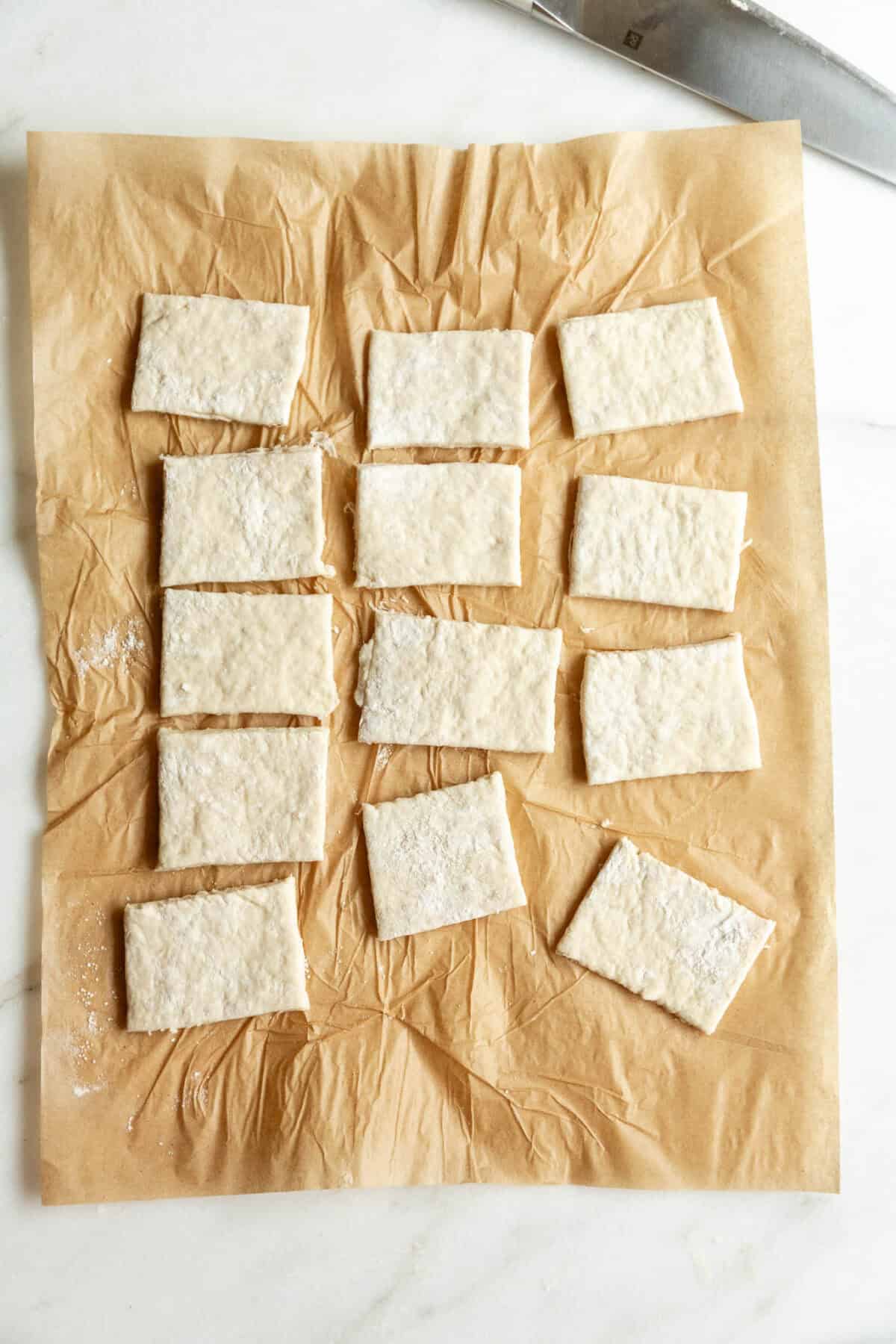 Cottage cheese dough cut into small rectangles on parchment paper.